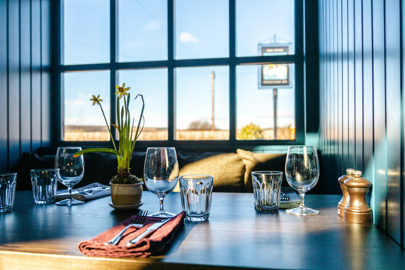 Table set up with glasswrar next to the window at Kinneuchar Inn